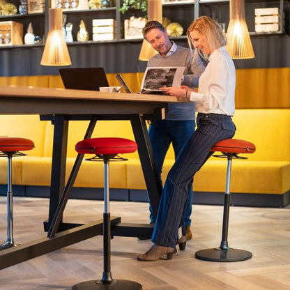 Twee personen op VILT Steady krukken aan een hoge tafel, perfect voor een flexibele werkhouding.