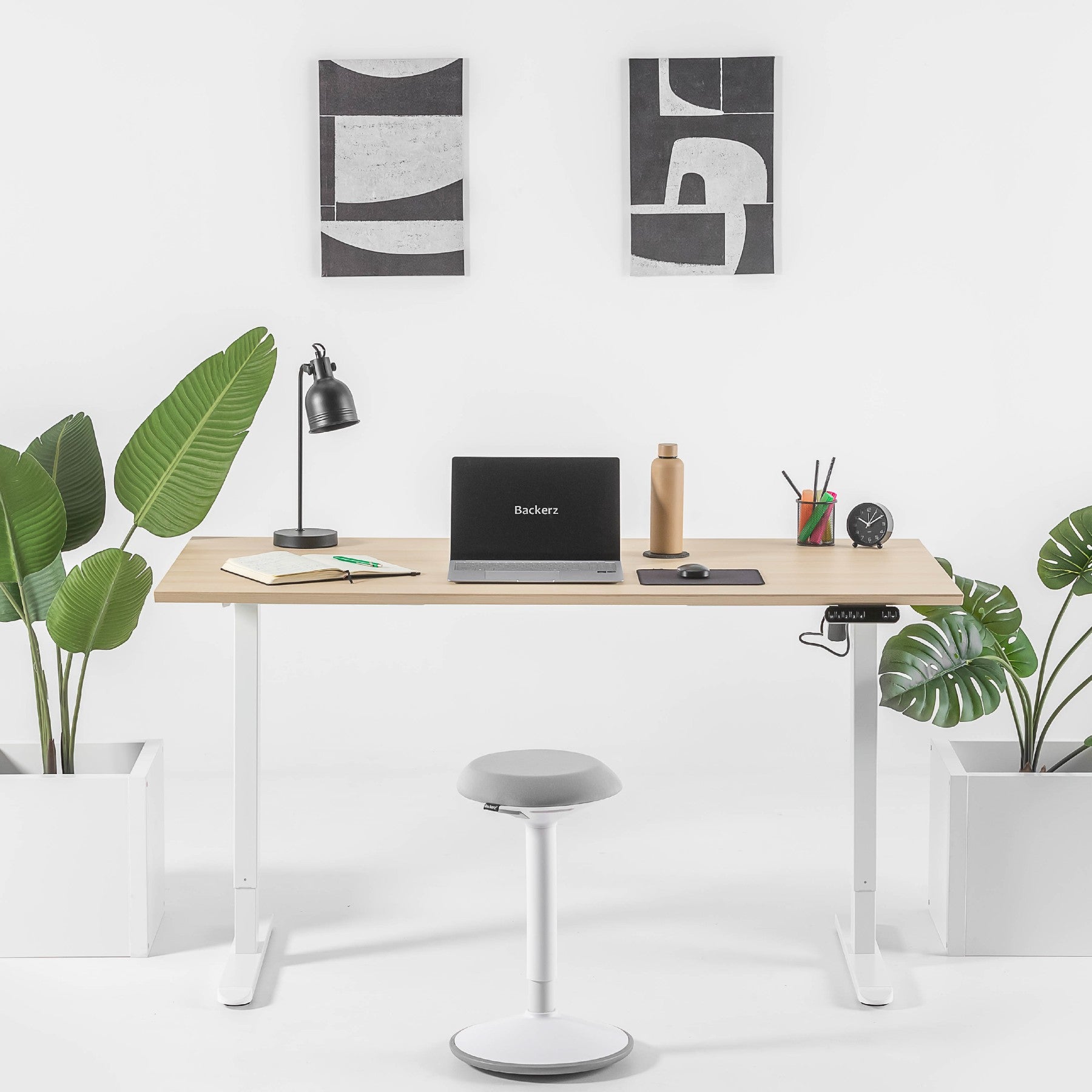 Een stijlvol wit bureau met laptop en twee planten, ideaal voor een inspirerende werkomgeving.