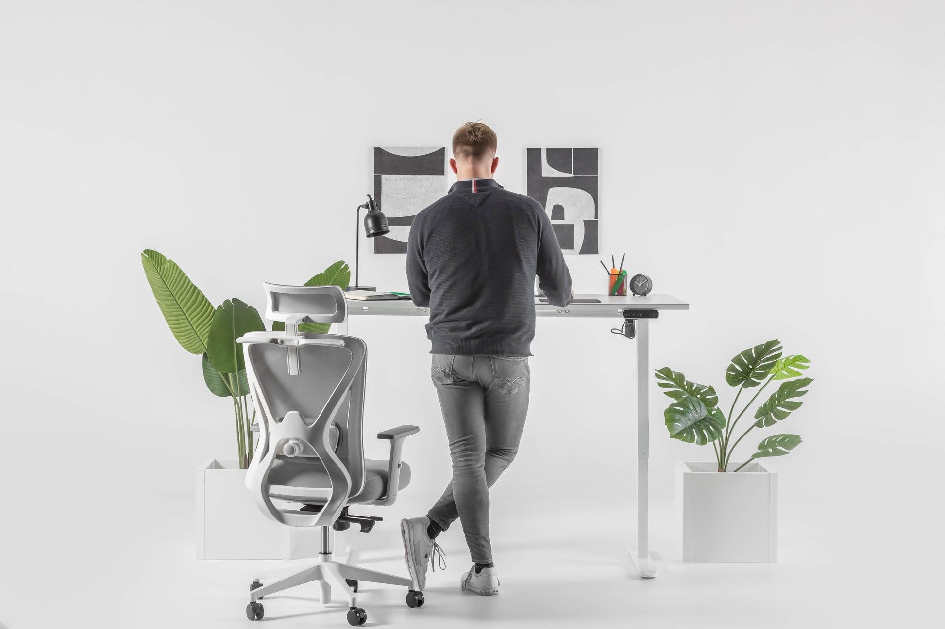 Een man zit achter zijn bureau met een computer en een plant, genietend van een productieve werkomgeving.