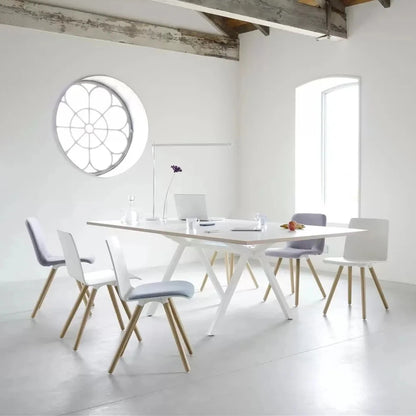 Witte vergadertafel met vier stoelen en een rond raam, ideaal voor een moderne werkomgeving en samenwerking.
