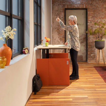 Vrouw in de HomeFit thuiswerkplek, staand voor een bureau met een computer.