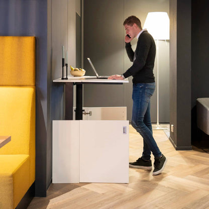 Een man staat aan een bureau met een laptop, genietend van zijn HomeFit thuiswerkplek voor een betere houding.