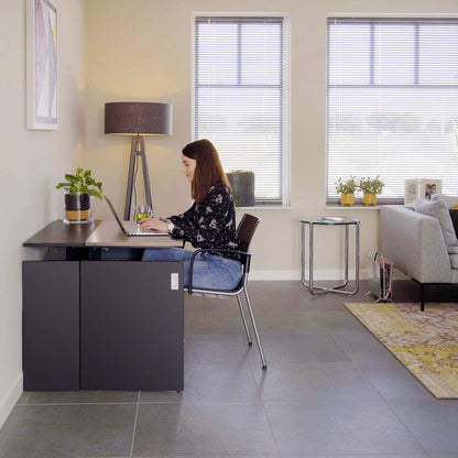 Vrouw achter een bureau in een kantoor, met een stijlvolle HomeFit thuiswerkplek.